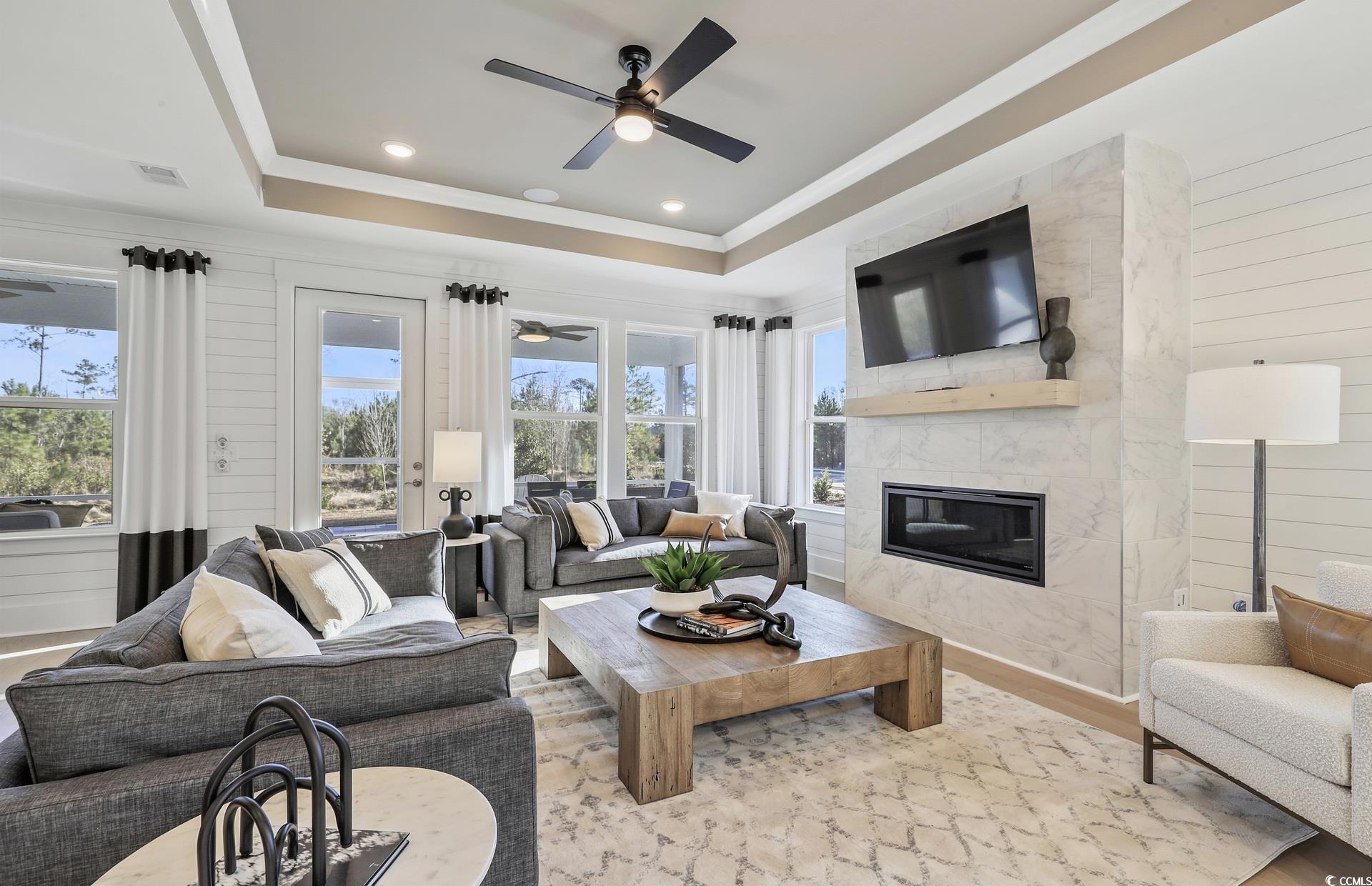 1514 Winding Crk Way Myrtle Beach, SC 29588 - Photo 5 of 20 Living room with wood walls, a high end fireplace, wood finished floors, ceiling fan, and a raised ceiling