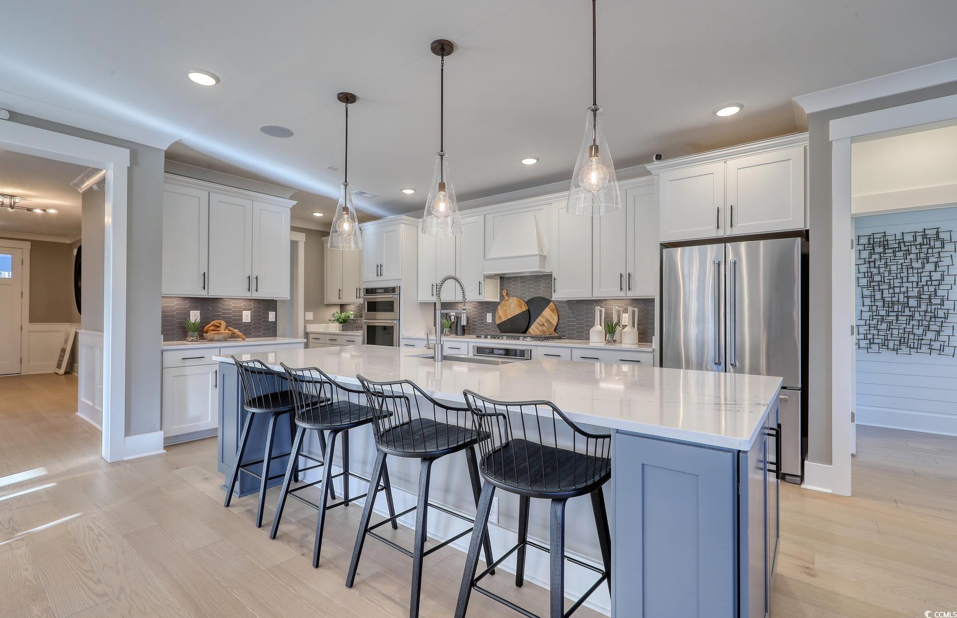 1514 Winding Crk Way Myrtle Beach, SC 29588 - Photo 6 of 20 Kitchen with white cabinets, appliances with stainless steel finishes, a breakfast bar area, hanging light fixtures, and recessed lighting