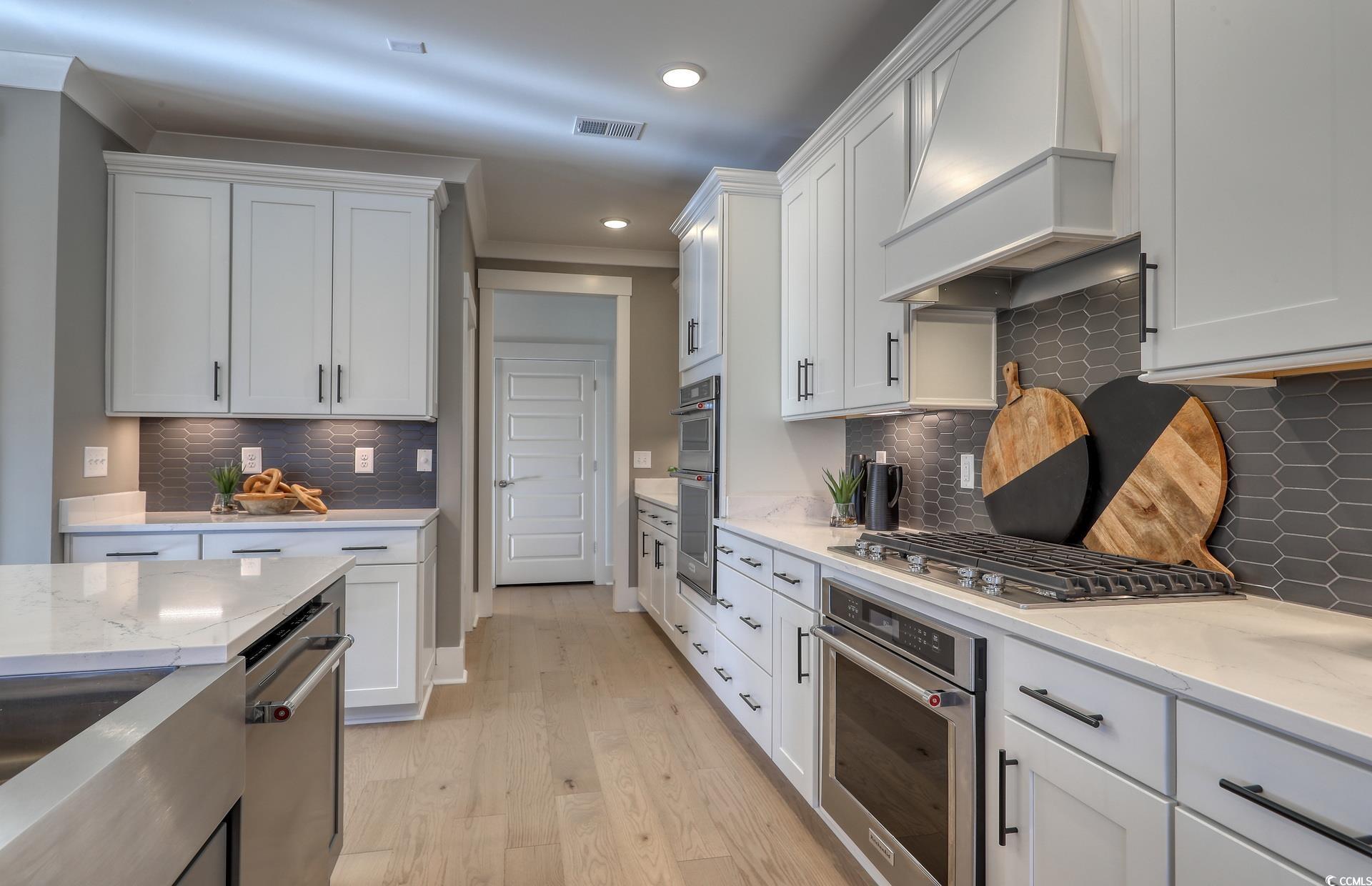 1514 Winding Crk Way Myrtle Beach, SC 29588 - Photo 9 of 20 Kitchen featuring custom exhaust hood, light stone counters, white cabinetry, light wood finished floors, and recessed lighting
