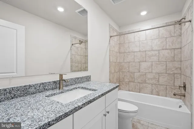 a bathroom with a granite countertop sink a toilet and bathtub