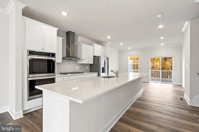 a large kitchen with stainless steel appliances a large counter top a stove and a refrigerator