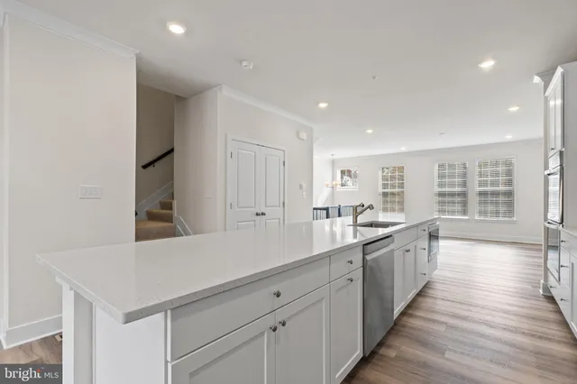 a large white kitchen with a sink and dishwasher with wooden floor