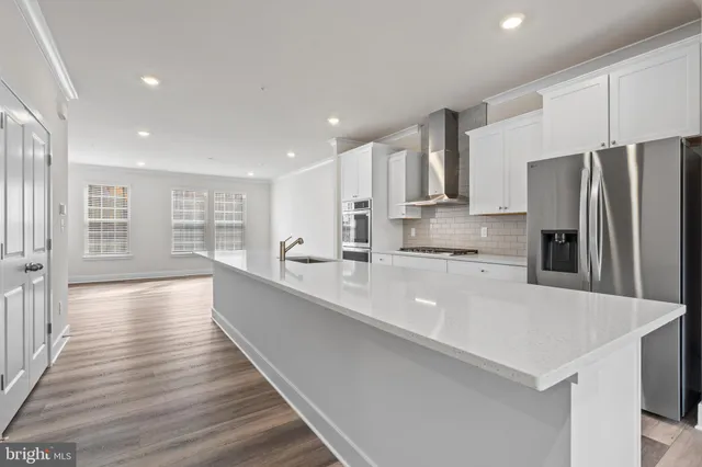 a large kitchen with stainless steel appliances a large counter top a stove and a refrigerator