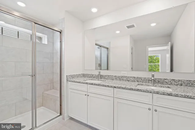 a bathroom with a granite countertop sink two mirror and a shower