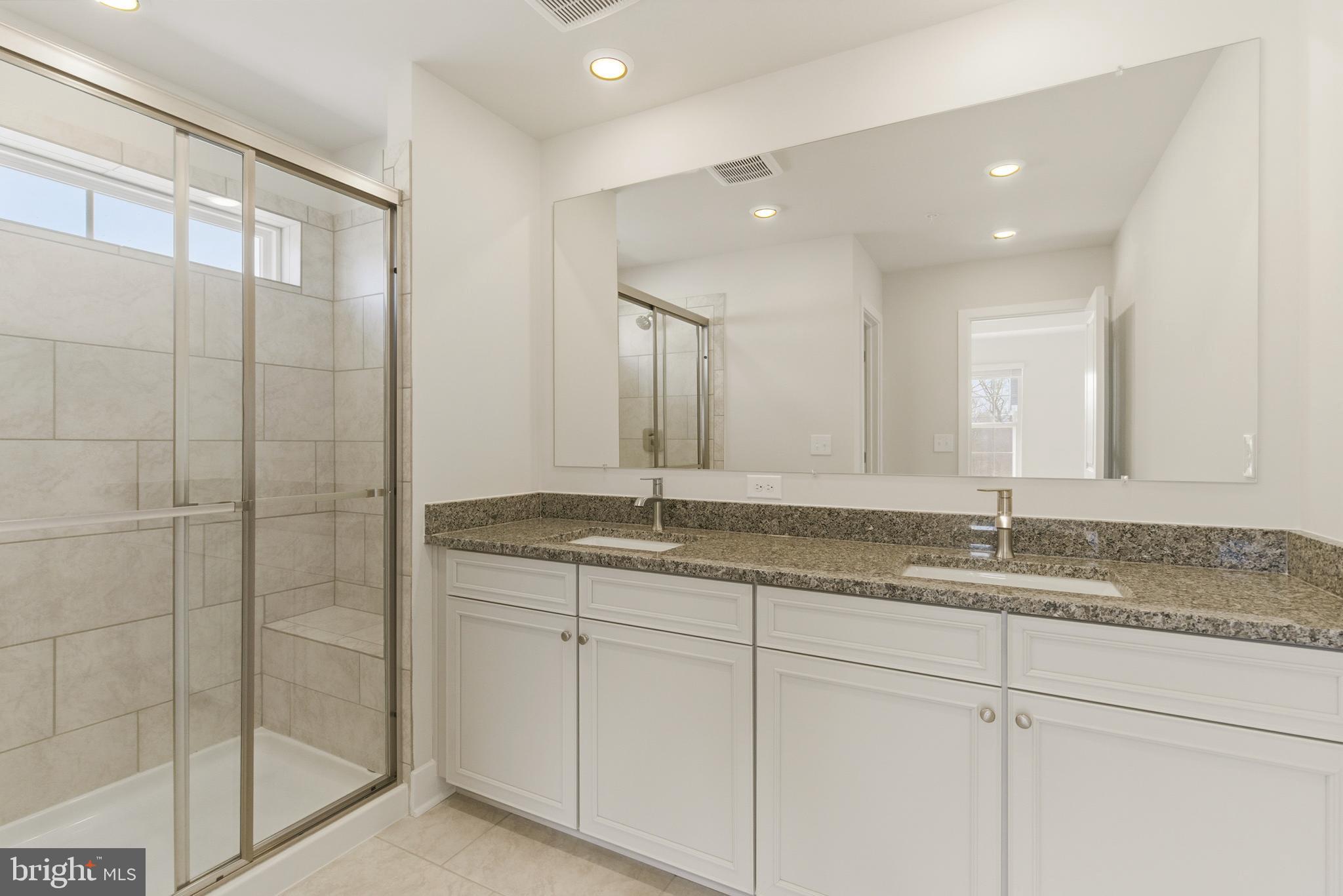 1723 Water Xing Road Pikesville, MD 21208 - Photo 24 of 37 a bathroom with a granite countertop sink a mirror and a shower