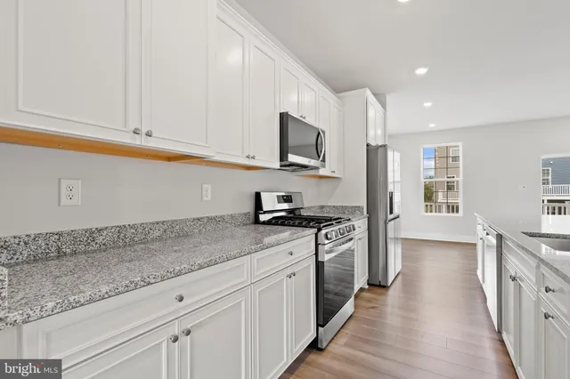 a kitchen with stainless steel appliances granite countertop a stove a sink and a refrigerator