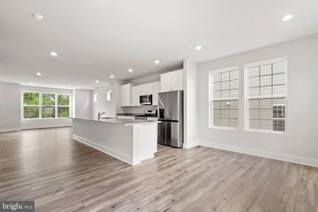 a large kitchen with stainless steel appliances granite countertop a large counter top a wooden floor and a window