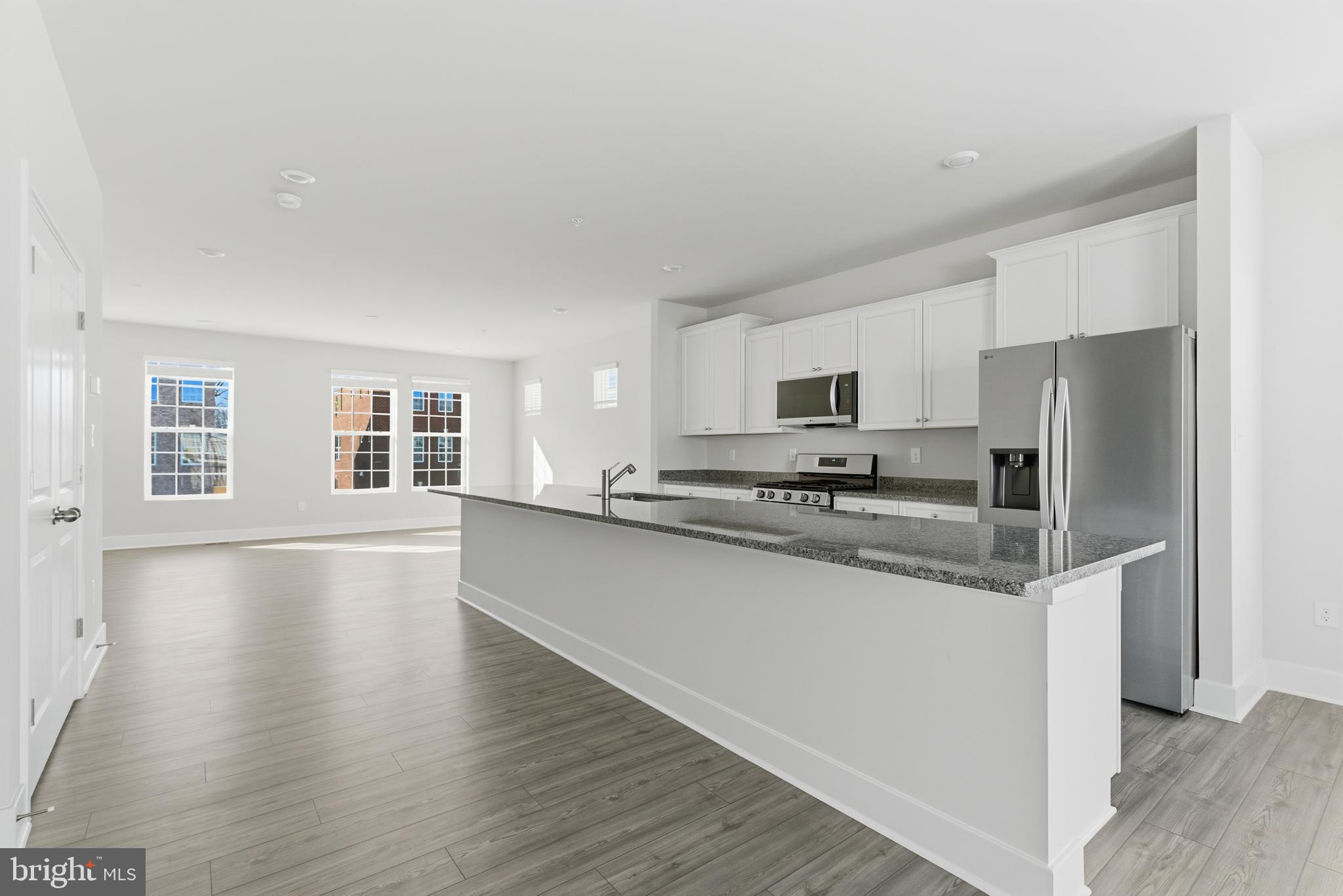 1723 Water Xing Road Pikesville, MD 21208 - Photo 9 of 37 a kitchen with stainless steel appliances granite countertop a refrigerator a sink dishwasher a stove and white cabinets with wooden floor