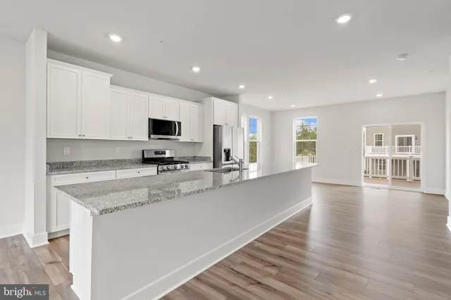 a large kitchen with stainless steel appliances granite countertop a stove a sink dishwasher and a microwave with wooden floor