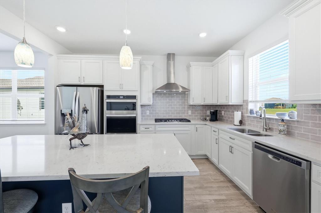 8706 Ocean Tides Cove Parrish, FL 34221 - Photo 14 of 63 a kitchen with stainless steel appliances kitchen island granite countertop a stove a sink a refrigerator and white cabinets with wooden floor