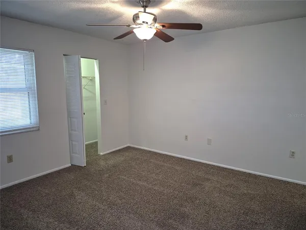 an empty room with a chandelier fan and windows