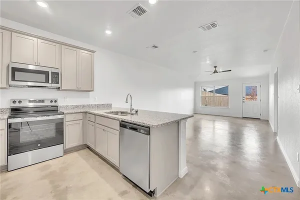 a kitchen with stainless steel appliances granite countertop a stove top oven a sink dishwasher and a refrigerator with wooden floor