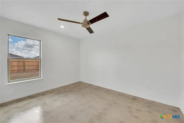 an empty room with a window and a ceiling fan
