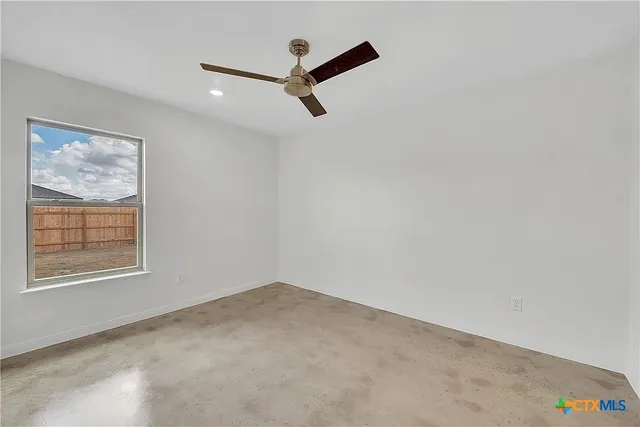 an empty room with a window and a ceiling fan