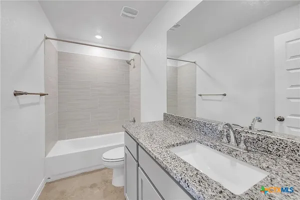 a bathroom with a granite countertop sink a toilet and shower
