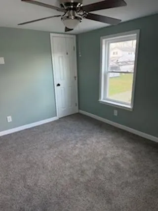 an empty room with a window and a fan