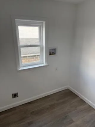 an empty room with wooden floor and a window