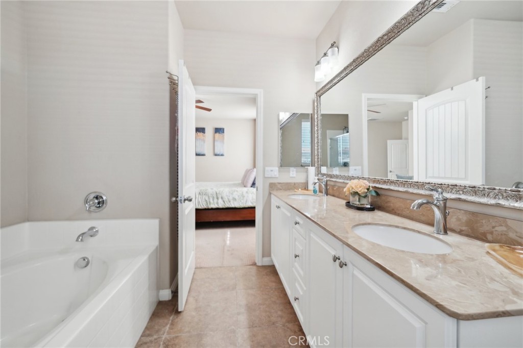 29259 Bouris Drive Menifee, CA 92584 - Photo 29 of 56 a bathroom with a granite countertop tub a double vanity sink and mirror