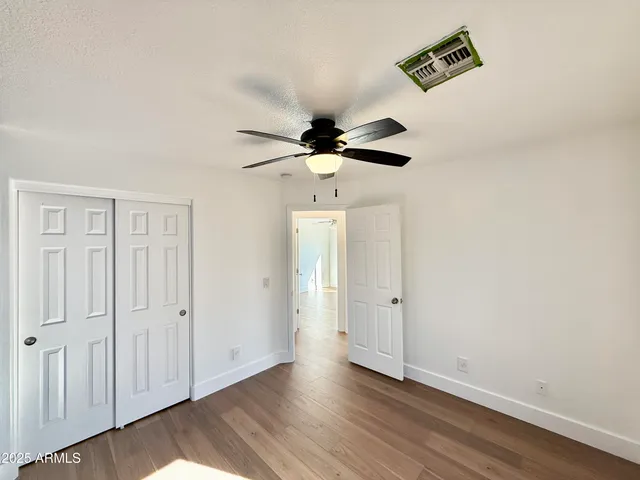 an empty room with wooden floor and ceiling fan