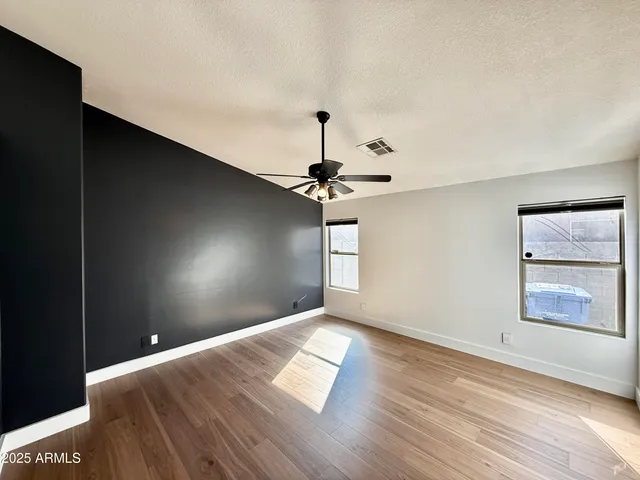 a view of empty room with wooden floor and fan