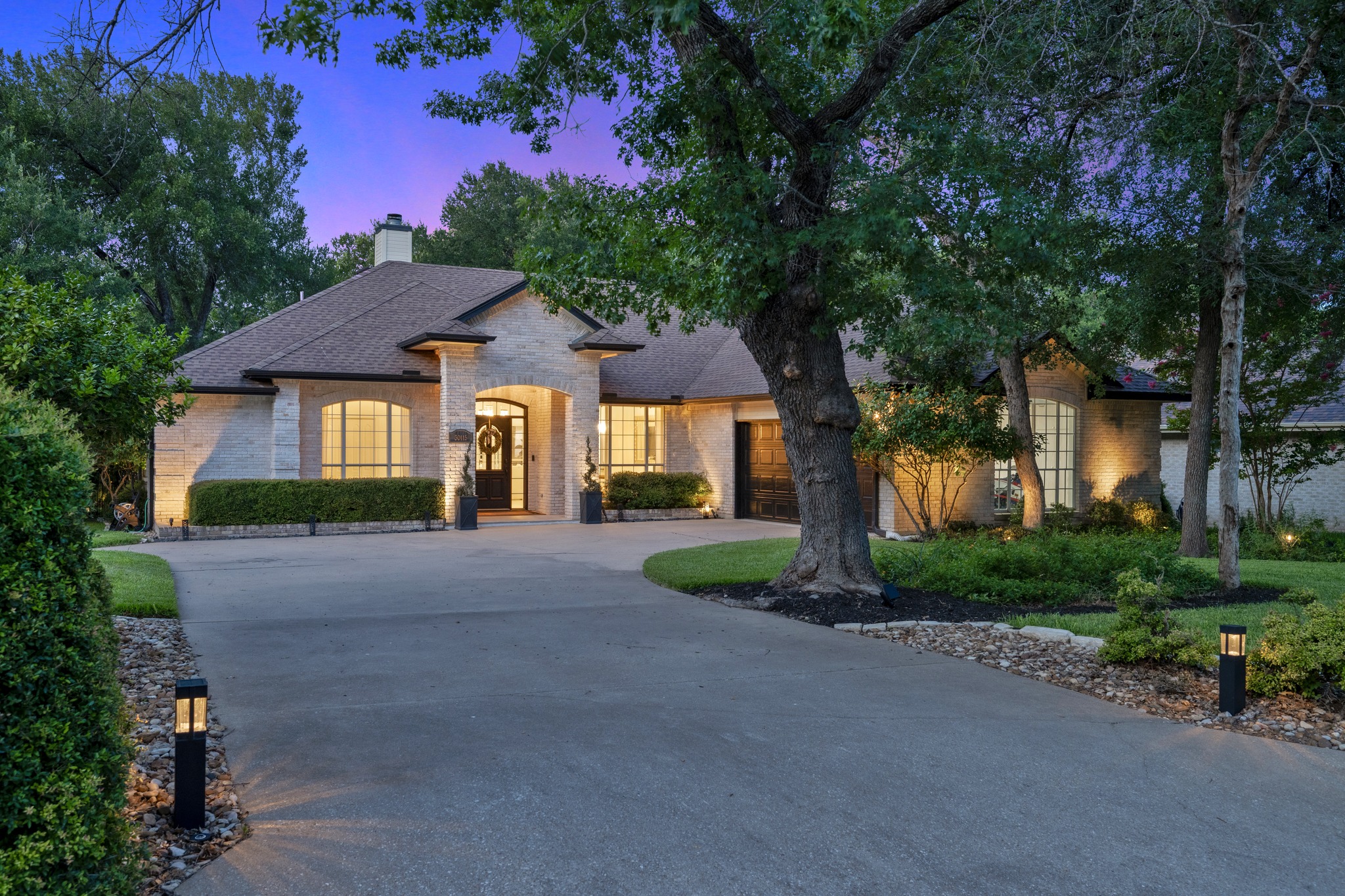 30115 Sawgrass Trail Georgetown, TX 78628 - Photo 3 of 37 A graceful residence with a circular driveway and mature trees offers an inviting facade under the twilight sky.