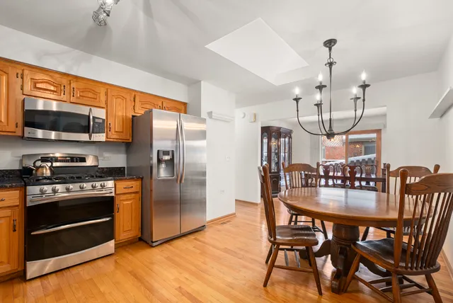 a kitchen with stainless steel appliances granite countertop a kitchen island hardwood floor and a view of living room