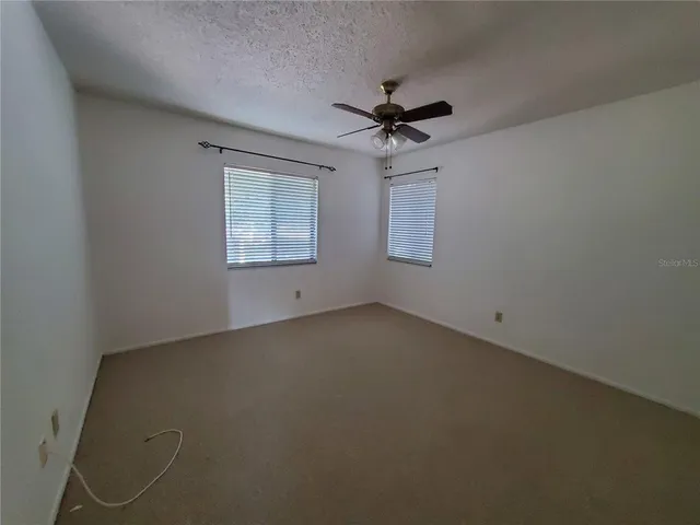 an empty room with a window and a fan