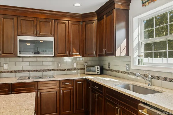 a kitchen with granite countertop stainless steel appliances a sink window and cabinets