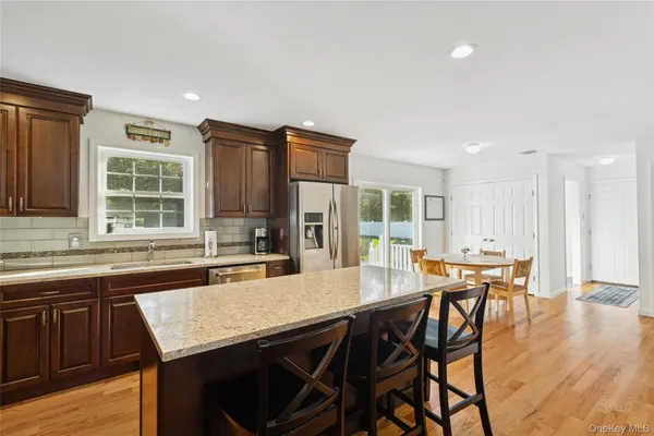 a kitchen with stainless steel appliances granite countertop a table chairs stove and refrigerator