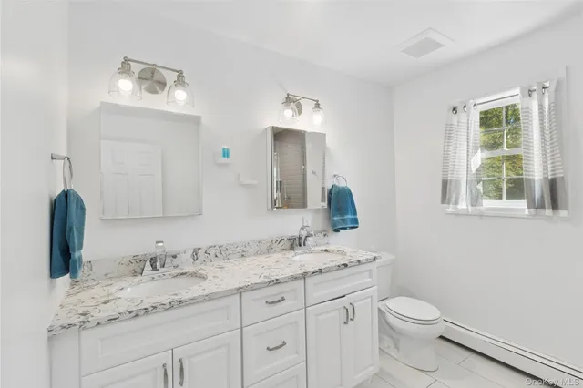 a bathroom with a granite countertop toilet sink and mirror
