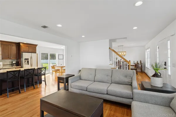 a living room with furniture kitchen view and a wooden floor