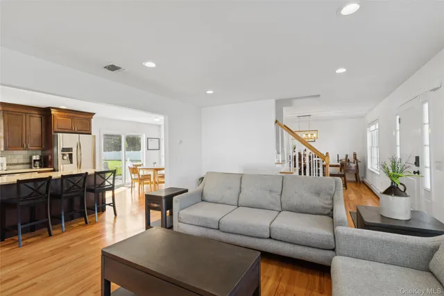 a living room with furniture kitchen view and a wooden floor