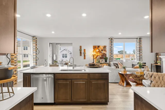 a open kitchen with stainless steel appliances granite countertop a sink dishwasher a stove and a dining table with wooden floor