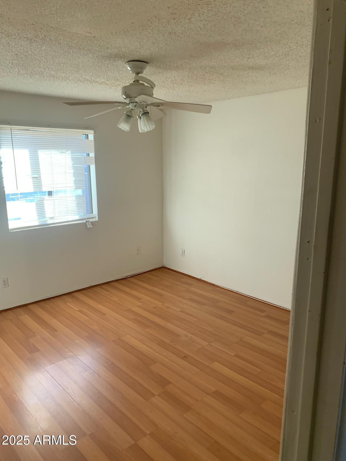 2419 East 10th Street Douglas, AZ 85607 - Photo 6 of 14 an empty room with wooden floor fan and windows