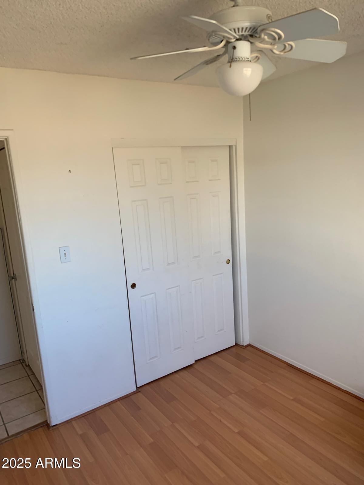 2419 East 10th Street Douglas, AZ 85607 - Photo 7 of 14 an empty room with wooden floor and fan