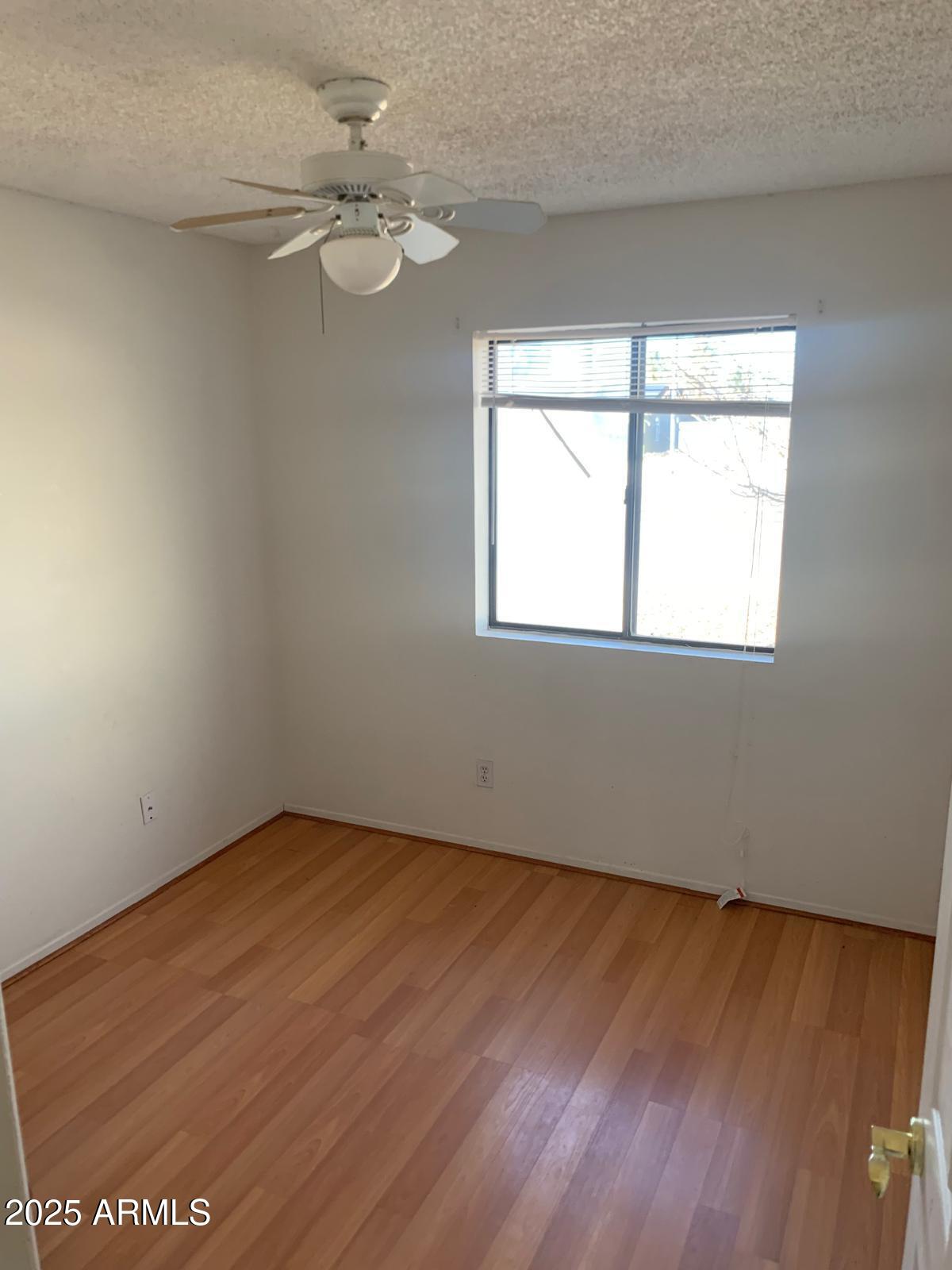 2419 East 10th Street Douglas, AZ 85607 - Photo 8 of 14 an empty room with wooden floor fan and windows