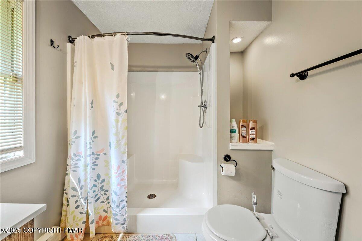 2102 Woodland Court Pocono Summit, PA 18346 - Photo 11 of 42 a bathroom with a shower curtain and a toilet