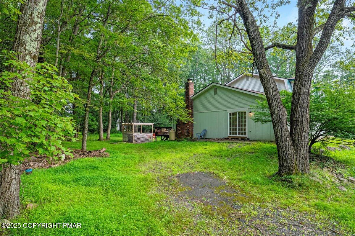 2102 Woodland Court Pocono Summit, PA 18346 - Photo 39 of 42 a backyard of a house with plants and large tree