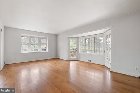 an empty room with wooden floor fireplace and windows