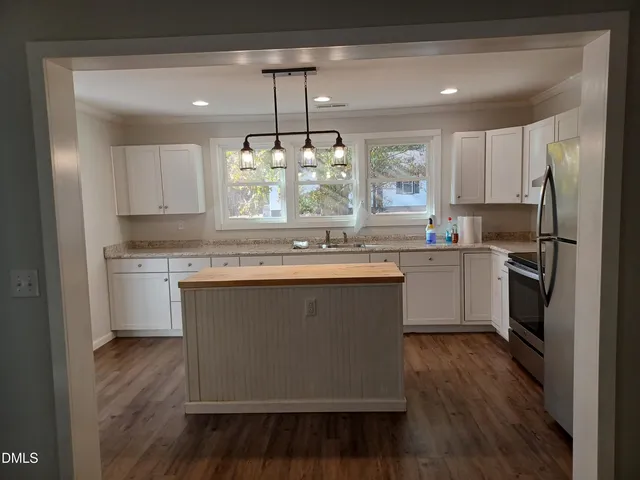a kitchen with kitchen island granite countertop a sink cabinets and wooden floor