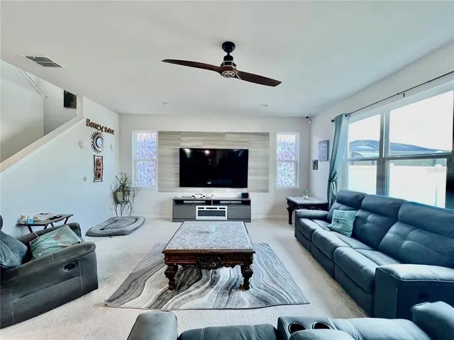 a living room with furniture a flat screen tv and a large window