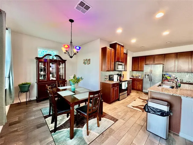 a dining room filled a chandelier and kitchen view