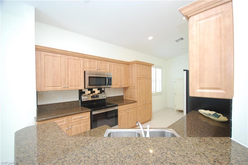 9200 Springview Loop Estero, FL 33928 - Photo 5 of 25 a kitchen with granite countertop a stove and a refrigerator