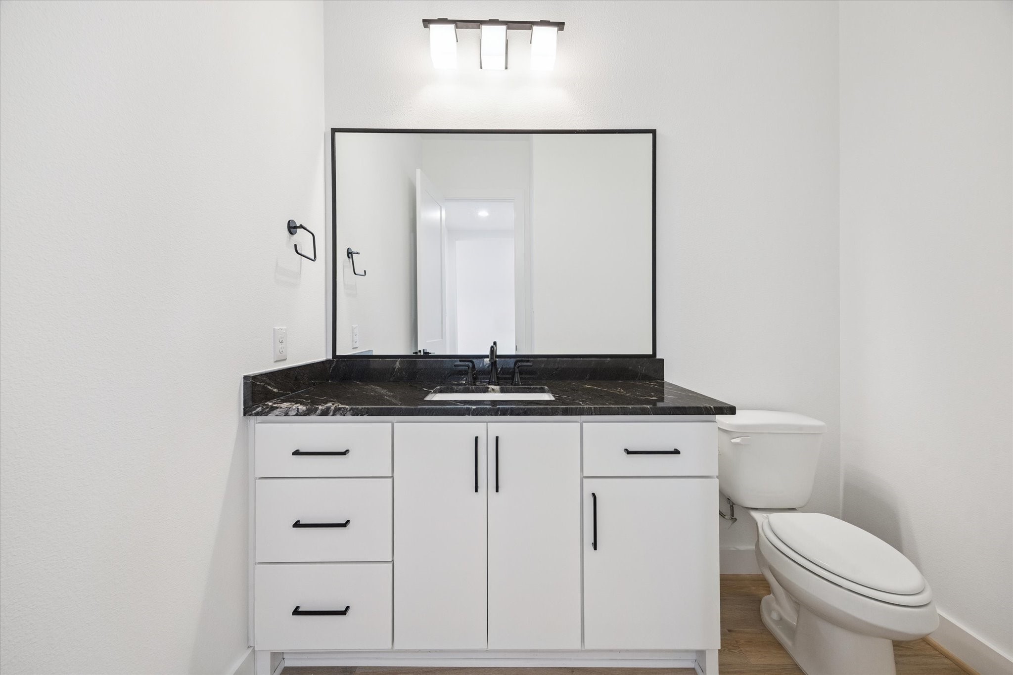 1201 Confederate Road Houston, TX 77055 - Photo 13 of 33 Bold and minimal, the half bath features a dramatic black stone countertop, sleek hardware, and modern lighting offering a polished, stylish touch for guests.