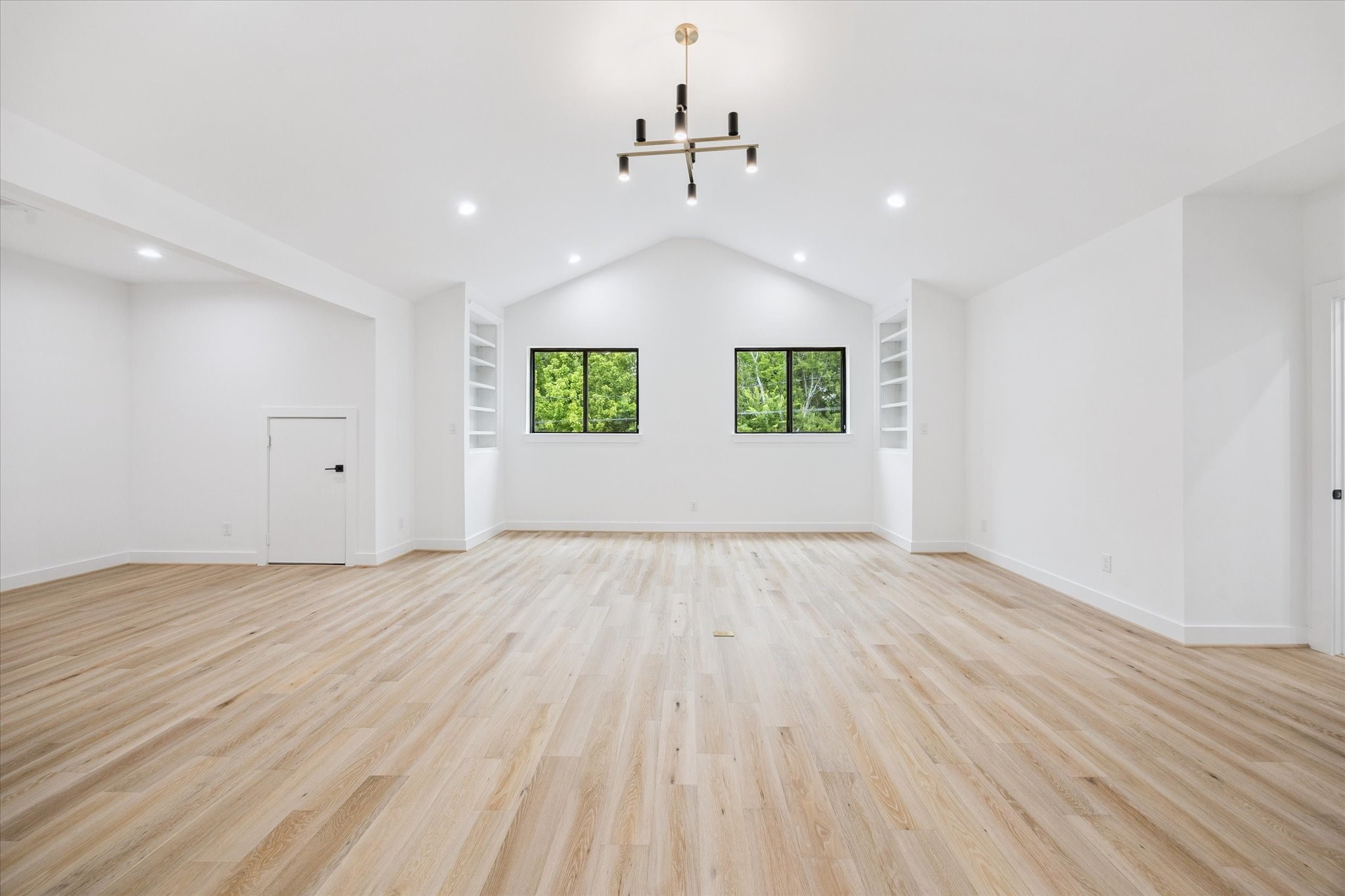1201 Confederate Road Houston, TX 77055 - Photo 15 of 33 Spacious upstairs game room with vaulted ceilings, built-in shelving, and modern lighting provides the perfect blank canvas for play, relaxation, or media. Twin windows frame views of the treetops, bringing in natural light and a sense of calm.
