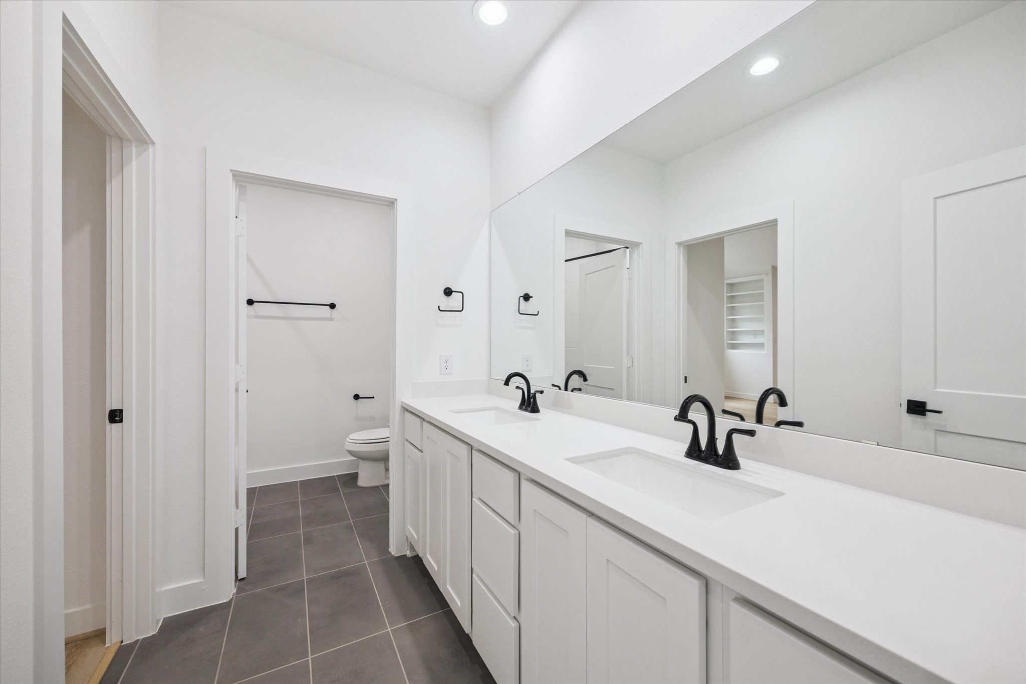 1201 Confederate Road Houston, TX 77055 - Photo 17 of 33 Dual sinks, matte black fixtures, and a sleek monochrome palette define this Jack-and-Jill bathroom. Accessible from both the game room and secondary bedroom, it’s designed for convenience without sacrificing style.