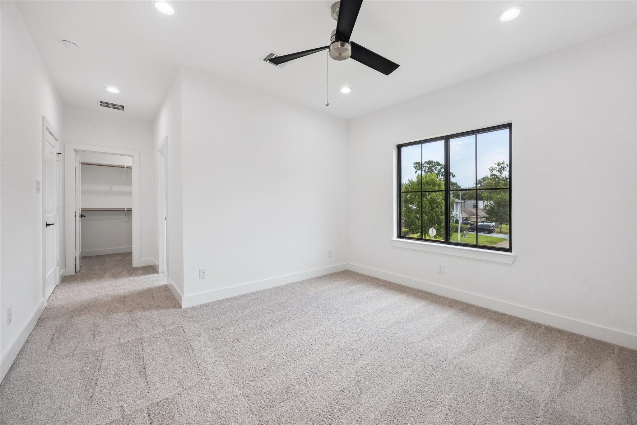 1201 Confederate Road Houston, TX 77055 - Photo 21 of 33 Bright natural light, plush carpeting, and clean lines give this secondary bedroom a calm, airy feel. Features include a walk-in closet, en-suite bath access, and a modern ceiling fan for year-round comfort.