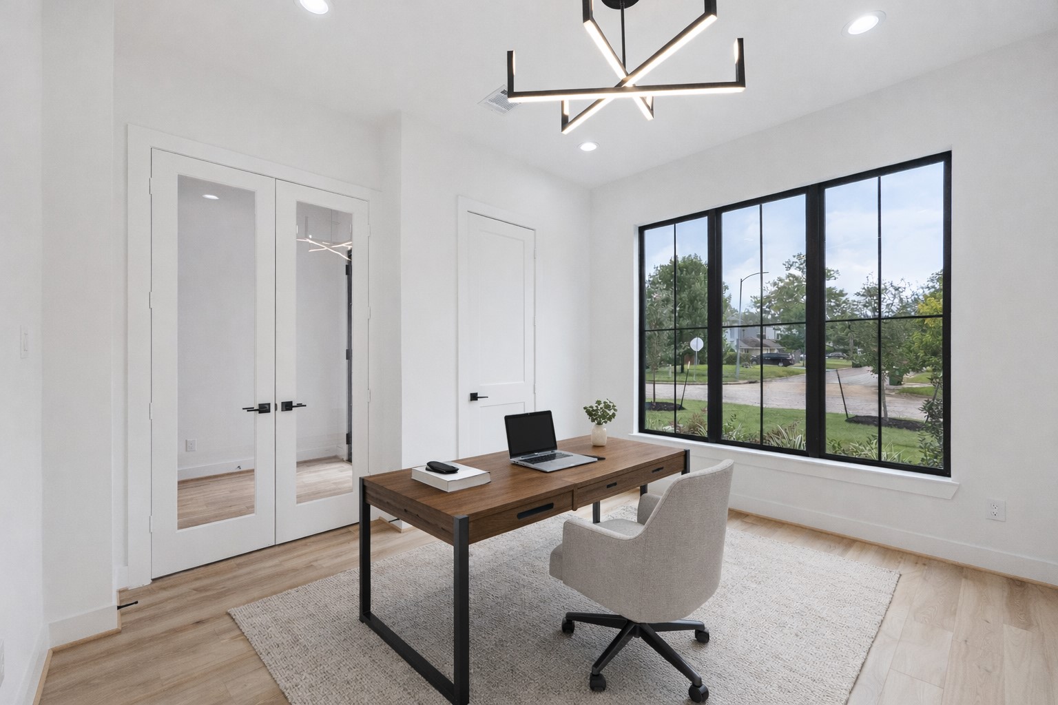 1201 Confederate Road Houston, TX 77055 - Photo 4 of 33 Framed glass doors open into a light-filled office, where bold lighting and wide-plank floors elevate the space. Oversized windows provide a direct view of the front yard and neighborhood, creating an energizing setting for focus and creativity. *Virtually Staged*