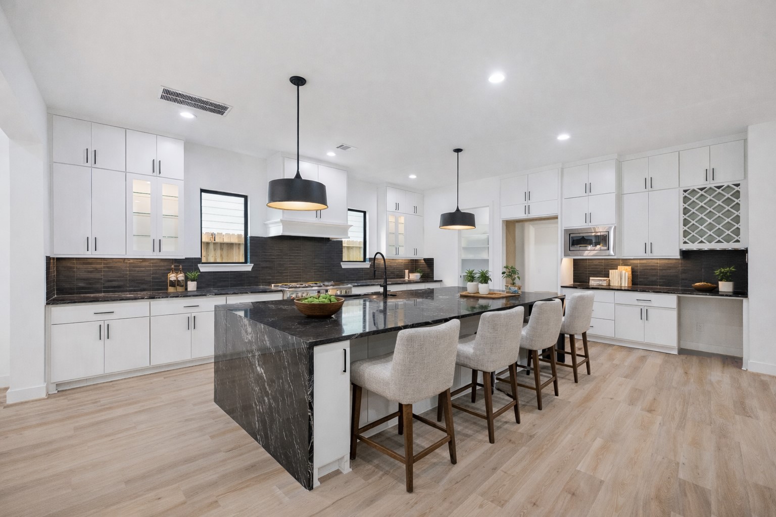 1201 Confederate Road Houston, TX 77055 - Photo 8 of 33 Bold contrast and streamlined design define this chef-worthy kitchen, featuring a dramatic waterfall-edge island, black tile backsplash, and modern pendant lighting. Ample cabinetry, a built-in wine rack, and pantry offer form and function. *Virtually Staged*