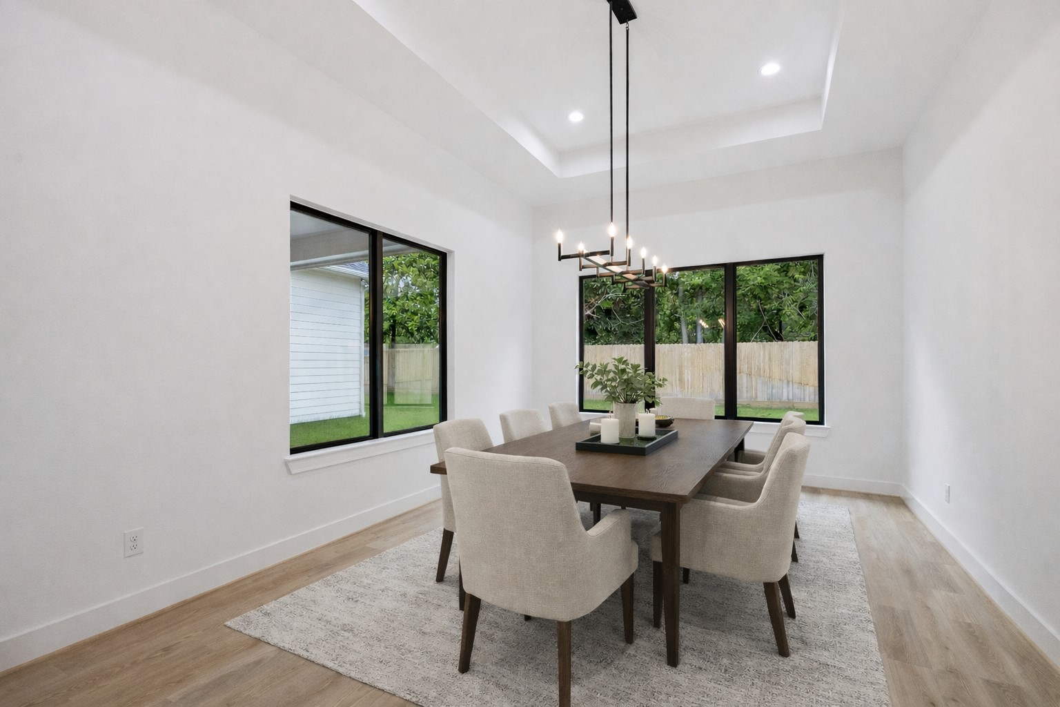 1201 Confederate Road Houston, TX 77055 - Photo 9 of 33 Walls of windows bring in natural light and views of the backyard, while a modern chandelier and tray ceiling add depth and sophistication to this versatile dining space. *Virtually Staged*